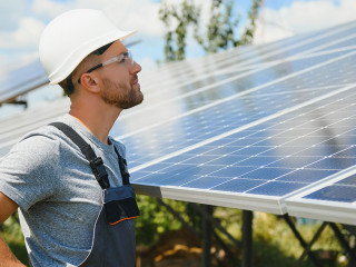 Male engineer in protective helmet installing solar photovoltaic panel system. Alternative energy ecological concept.
