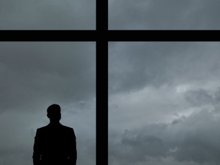 The man with suitcase standing near the big windows in the busin