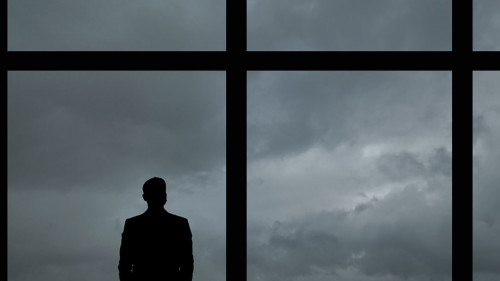 The man with suitcase standing near the big windows in the busin