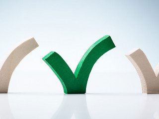 Green Check Mark Between Wooden Check Marks On Desk