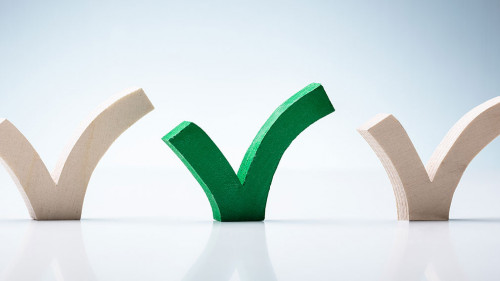 Green Check Mark Between Wooden Check Marks On Desk