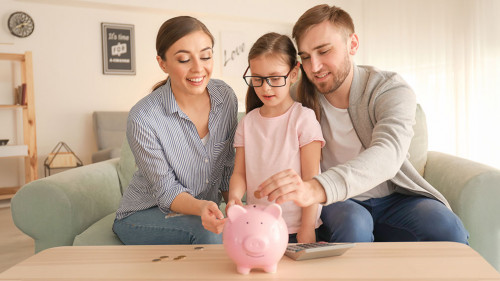Little girl with her parents putting coins piggy into bank indo