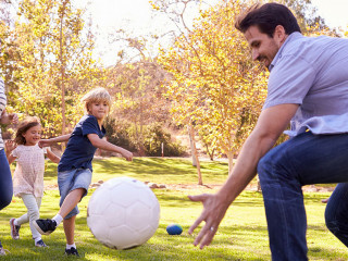 Family Playing Soccer In Park Together