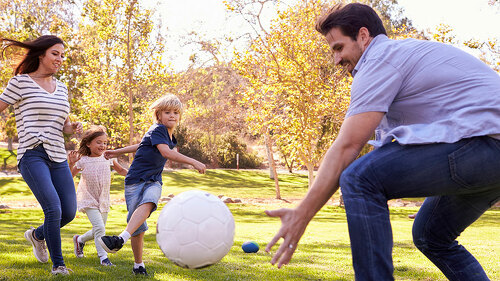 Family Playing Soccer In Park Together