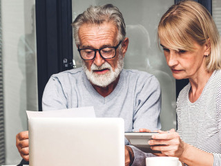 Senior couple reading documents and calculating bills to pay in