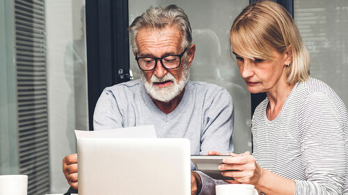 Senior couple reading documents and calculating bills to pay in