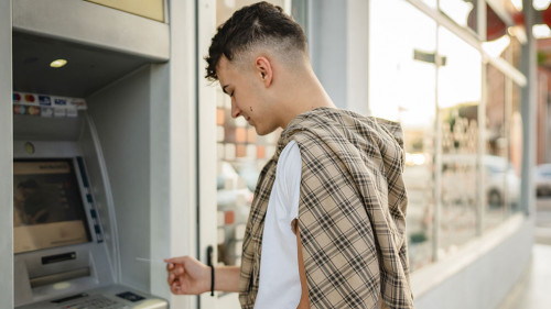 man teenage student using credit card and withdraw cash at the A
