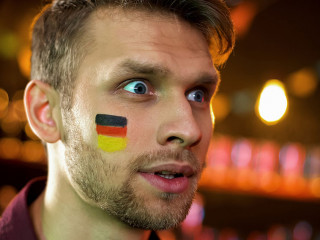 Bearded man with painted german flag surprised with results of championship