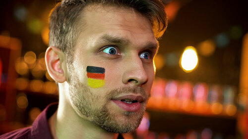 Bearded man with painted german flag surprised with results of championship
