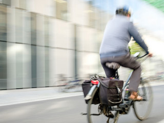 Mann fährt mit einem Pedelec im Straßenverkehr, Bewegungsunsch