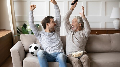 Excited man and old dad celebrate win watching football