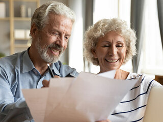 Senior couple use online banking on laptop planning family budget