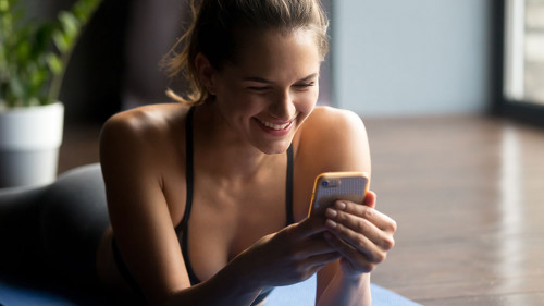 Young sporty woman holding smartphone, using app