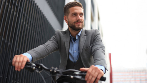 Handsome young businessman riding bicycle outdoors in the city.