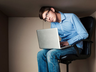 teenager, student in small office working on laptop, in an uncom