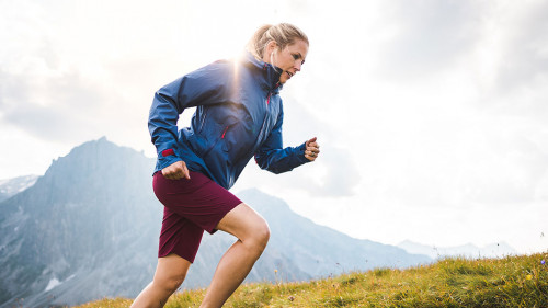 Sportive girl running on a trail through a beutiful Mountain Mea