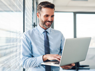 Handsome businessman in modern office looking on laptop