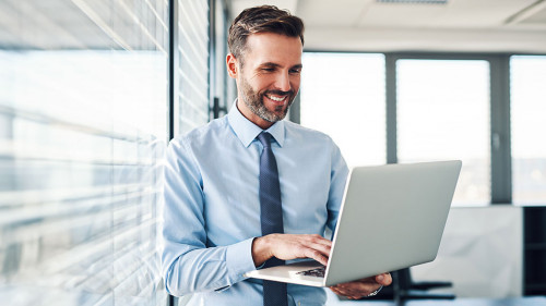 Handsome businessman in modern office looking on laptop