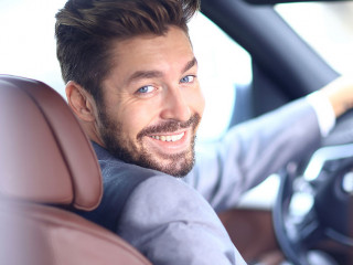 Portrait of an handsome smiling business man driving his car