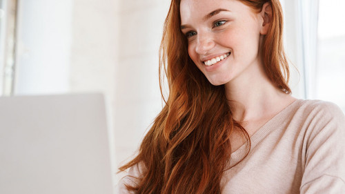 Cheerful young redhead lady sitting in classroom