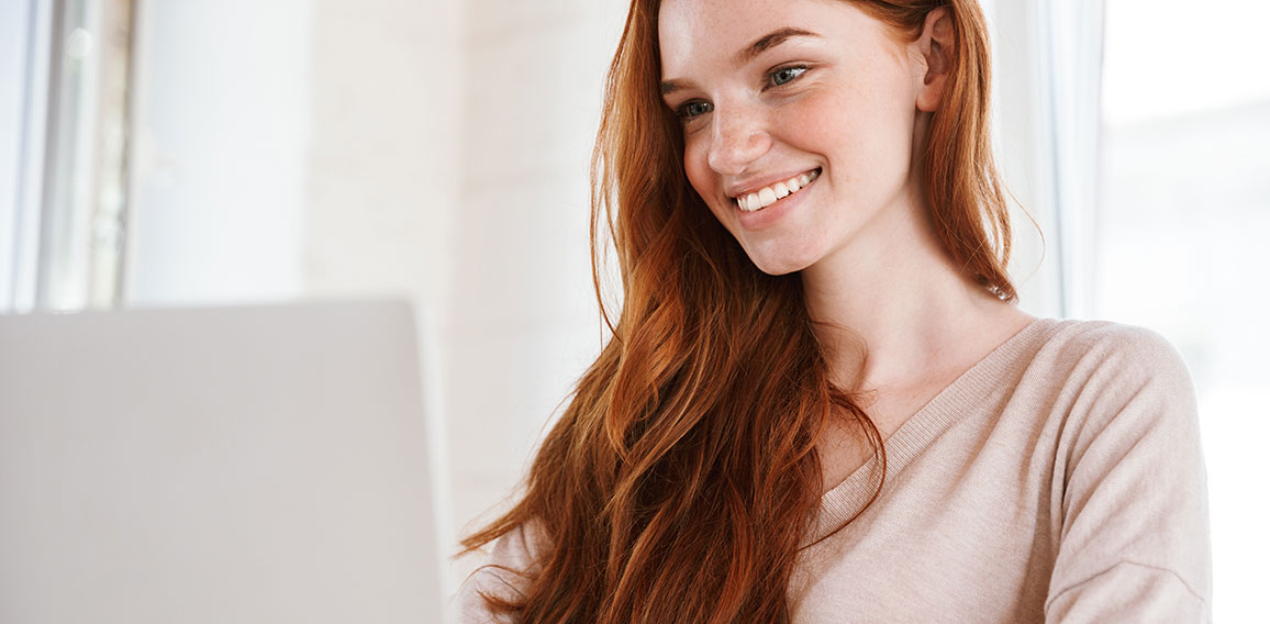 Cheerful young redhead lady sitting in classroom