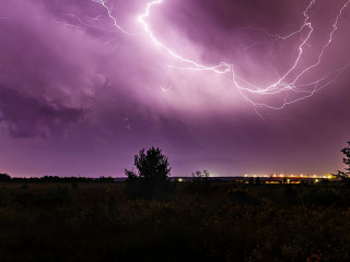 Lightning in the sky at night with a city in the distance