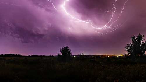 Lightning in the sky at night with a city in the distance