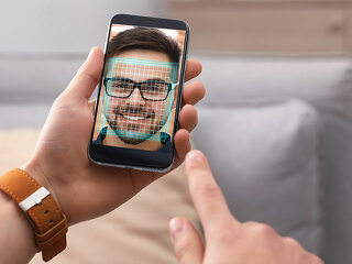 Man using smartphone with facial recognition system indoors, clo
