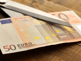 Scissors cuts euro banknote on wooden background
