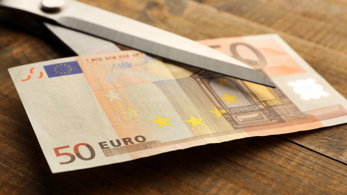 Scissors cuts euro banknote on wooden background