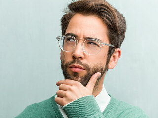 Young handsome entrepreneur man face closeup doubting and confused, thinking of an idea or worried about something