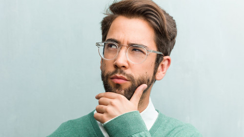Young handsome entrepreneur man face closeup doubting and confused, thinking of an idea or worried about something