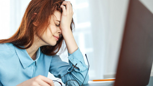 tired woman sitting at a table in front of a laptop work dissatisfaction