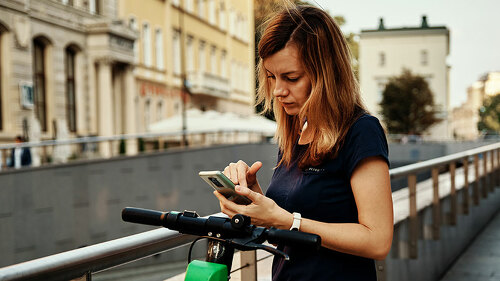 Woman unlock electric scooter for rent with a smartphone application