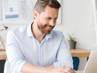 Smiling businessman working on laptop computer