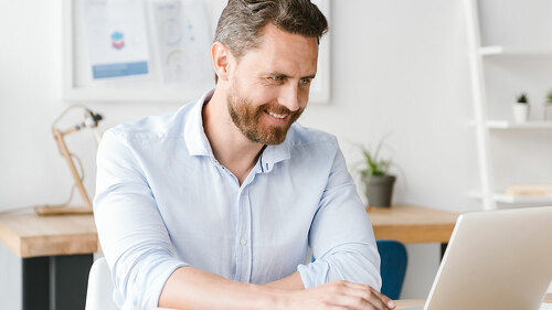 Smiling businessman working on laptop computer