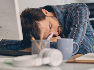 Tired young man taking nap at work