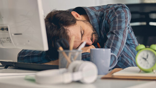 Tired young man taking nap at work