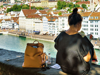 Girl sitting on Lindenhof hill and looking into book Zurich
