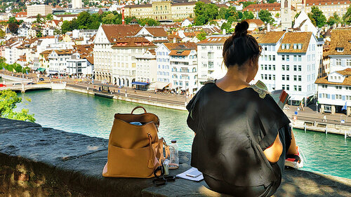 Girl sitting on Lindenhof hill and looking into book Zurich