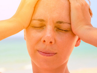 Young woman suffering with headache. Woman on hot beach with sunstroke. Health problem on holiday.