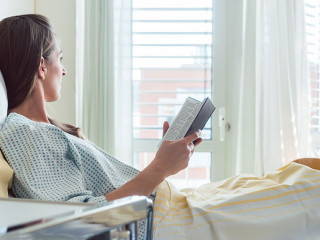 Patient in hospital room looking out of the window from bed