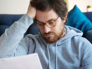 Frustrated disappointed guy reading a financial letter at home