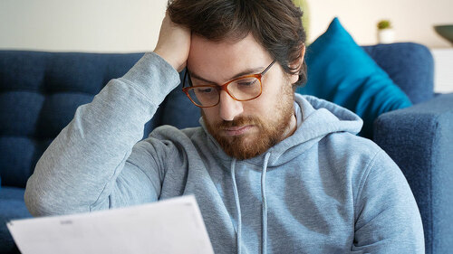 Frustrated disappointed guy reading a financial letter at home