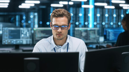 Night Office: Young Caucasian Man Working on Two Desktop Compute