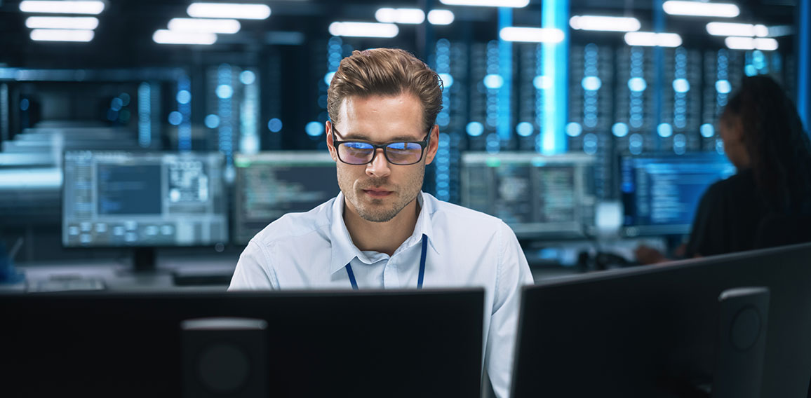 Night Office: Young Caucasian Man Working on Two Desktop Compute