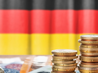 Geldscheine und Münzen vor der Nationalflagge Deutschlands