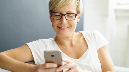 entspannte frau auf dem sofa schaut auf ihr handy