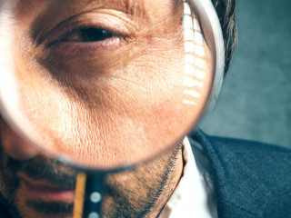 Enlarged eye of tax inspector looking through magnifying glass