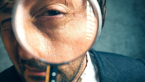 Enlarged eye of tax inspector looking through magnifying glass